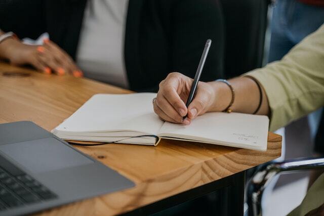 Person writing something in a notebook at their desk